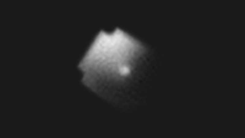 Image of a grey satellite against a black background. The satellite has rectangular body with missing squares in its corners. The left side of its body is much brighter than the right.